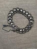 Full view of bracelet laid flat showing link pattern and safety chain