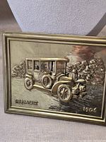 Full view of brass tone plaque showing Renault car relief