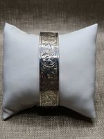 Front view of sterling silver floral engraved bangle on cushion