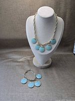 Necklace on bust form and bracelet laid flat showing overall design