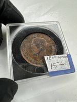 Coin obverse in plastic holder with handwritten label