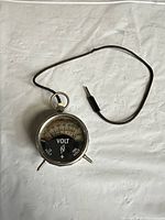 Front view of analog voltmeter with attached ring and separate probe lead