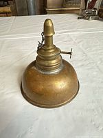 Overall view of brass and copper oil lamp showing reservoir and burner