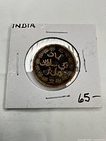 Obverse of coin in 2×2 holder showing Urdu script wreath