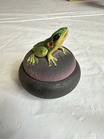 Oblique view showing frog figure on lid and color gradient