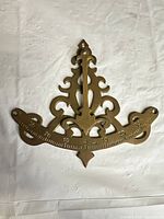 Front view of brass ornate protractor showing decorative design and graduated scale