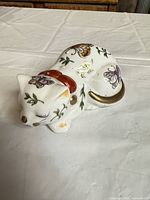 Top view of porcelain sleeping cat with butterfly and floral decoration