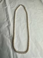 Full view of pearl necklace lie flat to show length and uniformity