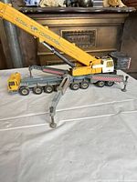 Side view of yellow mobile crane toy with boom extended and outriggers deployed