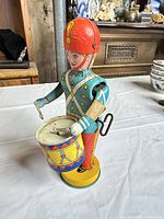Front left view of tin drummer soldier showing uniform, drum, key and base