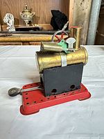 Left side view of Mamod brass steam engine on red base