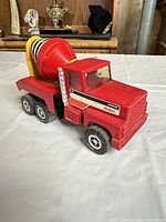 Front and side view of red Nylint cement mixer toy truck showing cab, wheels and mixer barrel