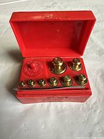Open case showing all brass weights and tweezer