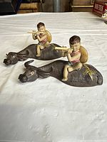 Both ceramic child-on-water-buffalo figurines side by side