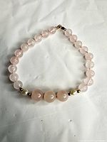 Full view of rose quartz and pearl bracelet laid flat