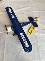 Angled top view of navy blue Chargers biplane with yellow “Go Chargers” tag showing overall form and paint wear
