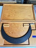 Micrometer in open wood case showing frame and thimble