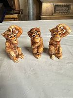 Front view of three brown ceramic monkey figurines on table