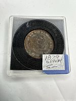 Coin obverse in plastic holder with handwritten label