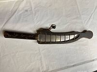 Full view of sword in scabbard showing overall shape, blade section, handle and scabbard carvings