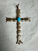 Front view of sterling silver cross pendant showing turquoise stone and scalloped arm design