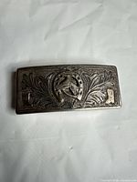 Front view of sterling silver rectangular buckle showing foliate engravings and horseshoe motif