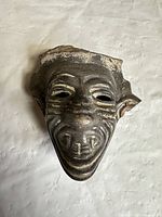 Front view of terracotta mask showing facial features and patina