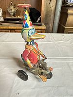 Front view of tin wind-up duck toy on three-wheel base
