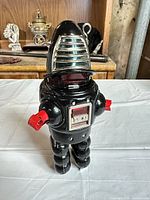 Front view of black tin robot with red arms and chest panel