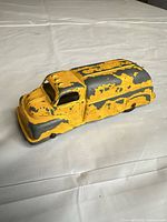 Front and side view of yellow die-cast toy car showing overall form and paint wear