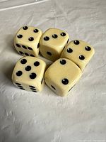 Five of six large cream dice showing size, color and pip style
