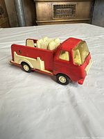 Overall view of vintage red toy fire truck showing cab, hose reel and wheels