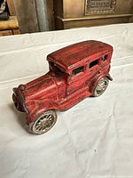 Left side view of red cast iron sedan toy car showing body shape and wheels