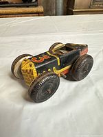Side perspective of tin wind-up race car showing litho graphics and wheels