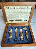 Overall view of open wooden display box showing certificate, four knives, medallion