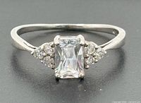 Front view of sterling silver ring showing emerald-cut center stone and side accent stones