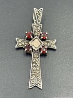 Front view of sterling silver cross pendant showing marcasite and garnet stones