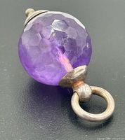 Full view of amethyst pendant showing faceted surface, silver cap and bail
