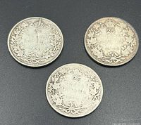 Reverse of three Canadian 25-cent coins showing wreath design and dates