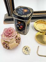 Group showing tin, rhinestone rose box, political pin, compact and winding key