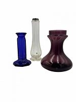 Front view of the three glass items: cobalt candlestick, clear ribbed bud vase, amethyst squat vase