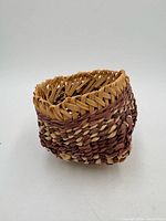 Angled view of handmade basket showing two-tone weave and open rim