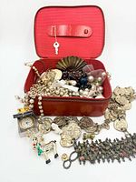 Overview of red leather case open with assorted jewelry spilling out