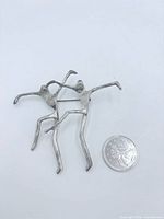 Front view of sterling silver brooch beside quarter for scale