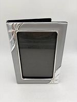 Front view of silver-tone metal photo album showing 5x7 frame and floral accents