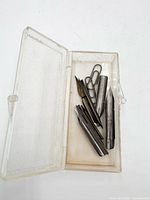 Open plastic case showing six metal nibs and paperclip