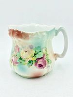 Front and side view of porcelain shaving mug showing floral design and scalloped rim
