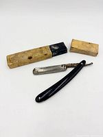 Straight razor opened beside two-piece yellow box