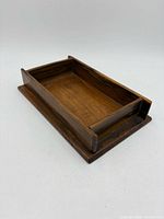 angled view of wooden trinket box with open top on base