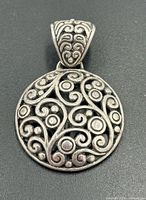 Front view of round filigree pendant with ornate bail